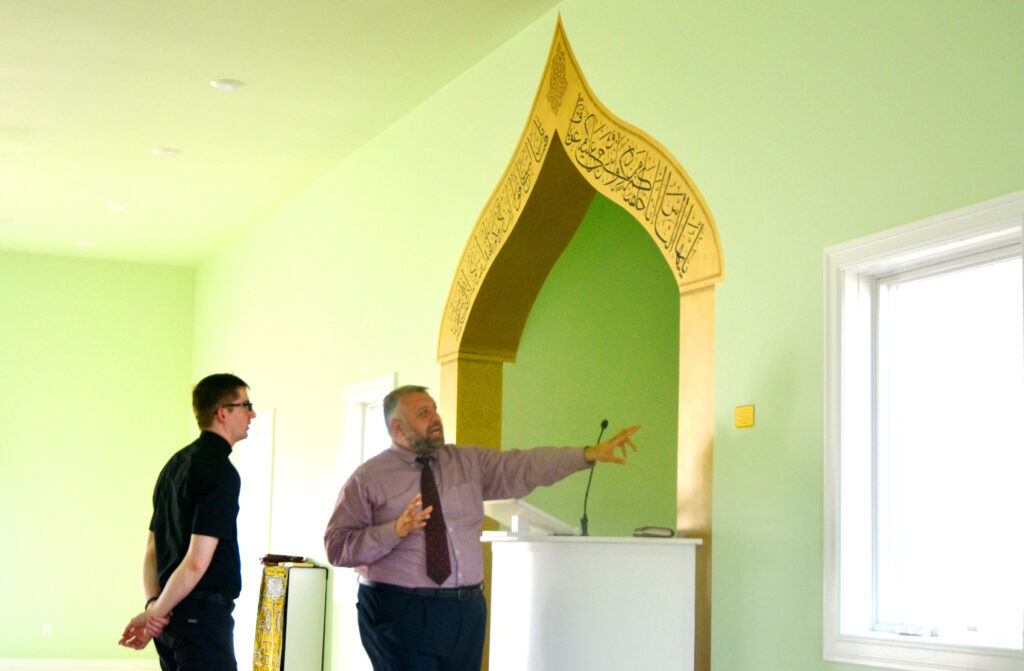 Father Alan Dietzenbach listens to Adib Kassas, acting imam at the mosque in Dubuque, Iowa, speak about Arabic calligraphy and the decoration around the arch April 26. The artwork was a gift from Catholic parishes in Dubuque to the center as a sign of friendship. (CNS photo/Dan Russo, The Witness) See PARISHES-ART-MOSQUE May 8, 2018.